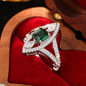 Detailed close-up of emerald cut green gemstone ring with marquise zircons in a velvet box