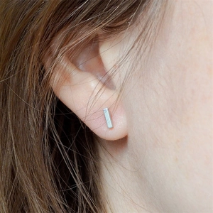 Minimalist rectangular silver stainless steel stud earring on female ear model