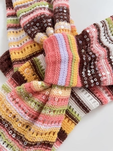Nahaufnahme von bunt gestreiftem Strickstoff mit glänzenden Pailletten und Textur