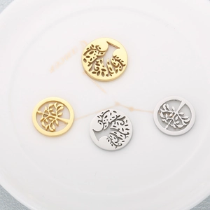 Detail showing gold and silver hollow Tree of Life charms on a ceramic plate