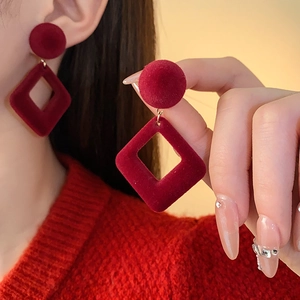 Gros plan de boucles d'oreilles géométriques rouges avec sphère et losange en velours doux