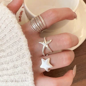 Three-piece silver star rings worn by model featuring multi-layer and starfish designs