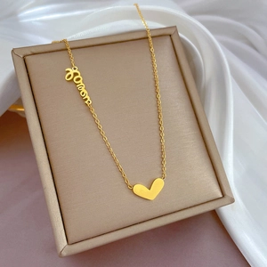 Dettaglio collana in acciaio al titanio dorato con pendente a cuore e love in cofanetto