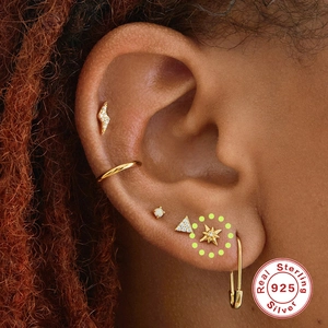 Macro shot of 925 sterling silver earring set featuring lightning and star studs on ear