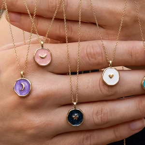 Close-up of gold-plated enamel pendants featuring celestial and heart designs on necklaces