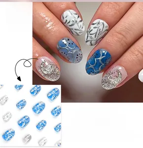 Detail of short round press-on nails featuring blue moon designs and silver glitter accents