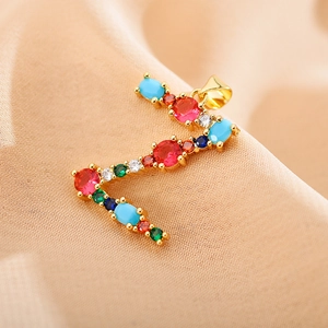 Macro detail of letter E pendant featuring colorful cubic zirconia on gold metal