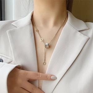 Collier doré élégant avec pendentif cylindre œil-de-chat sur un mannequin en costume
