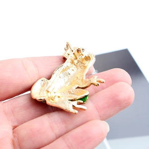 Macro detail of frog brooch back showing golden metal plating and secure pin fastener