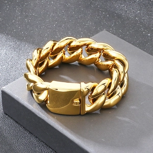 Detailaufnahme eines massiven goldenen Panzerarmbands mit Kastenverschluss auf grauem Sockel