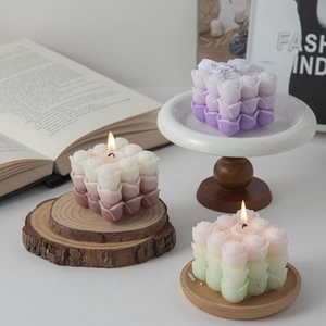 Flower cube scented candles in purple, red, and green gradients on a wooden tray