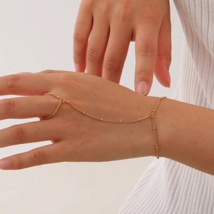 Minimalist gold stainless steel hand chain ring bracelet for women on white background