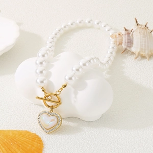 Detailed view of heart pendant pearl necklace with rhinestones on beach decor