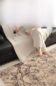 Detailed texture of artistic floral rug and faux cashmere throw on living room floor