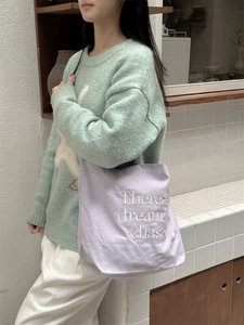 Detail of lavender canvas tote with white 'There is a dream chase' embroidery and texture