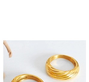 Close-up of golden croissant style rings with textured twisted rope pattern design