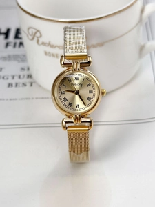 Detailed close-up of a gold mesh strap watch with Roman numeral dial on elegant background