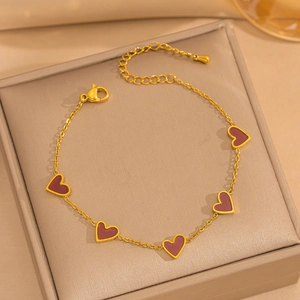 Detail of 18K gold-plated bracelet featuring five dark red enamel heart charms and lobster clasp