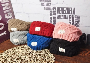 Close-up of colorful knitted winter hats stacked on a wooden table with woven mat