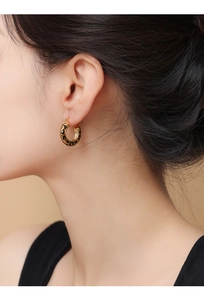 Close-up of 14k gold plated leopard print hoop earring worn on model's ear