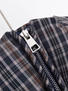 Close-up of silver metal zipper and plaid woven fabric on short quilted jacket