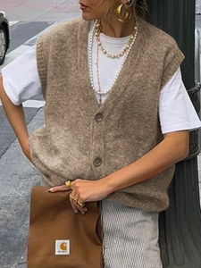 Dettaglio di un gilet in maglia marrone con scollo a V, bottoni e morbido tessuto