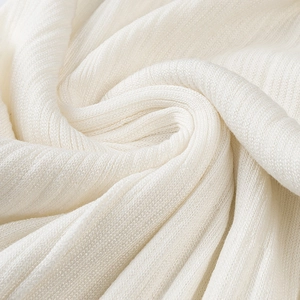 Close-up of soft white knitted fabric texture showing premium weave detail on dress