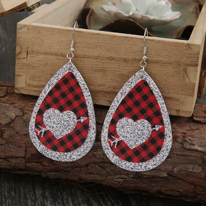 Close-up of teardrop leather earrings with red buffalo plaid and silver glitter heart pattern