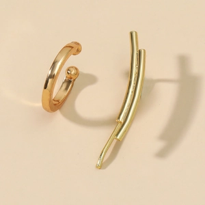 Detailed view of polished gold geometric ear cuffs and curved stud earrings on beige base