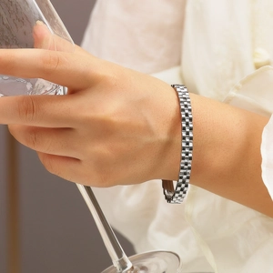 Detail of silver stainless steel jubilee strap bracelet on wrist holding a glass