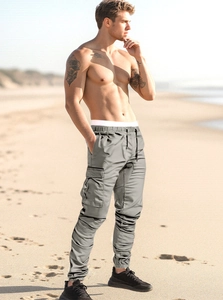Detail of men's grey cargo joggers with side pockets and drawstring on sunny beach