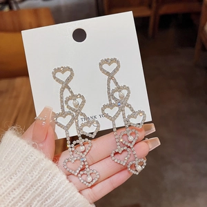 Close-up of long tassel earrings with sparkling heart crystals and pearls