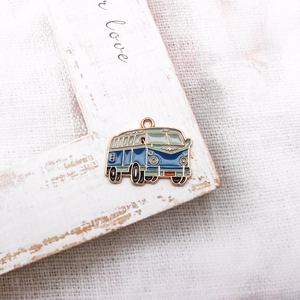 Detail of vintage enamel camper van pendant in blue and light green with golden metal edges