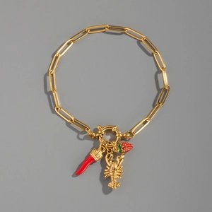 Macro view of 18K gold plated paperclip bracelet with strawberry and chili charms