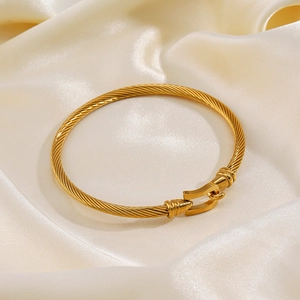 Gold plated stainless steel cable bracelet with a horseshoe buckle on white silk