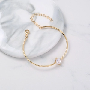 Detail of gold bracelet with square zircon and lobster clasp on marble tray