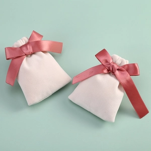 Macro detail of small light pink velvet jewelry pouches with dark pink ribbon bows