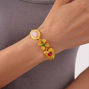 Close-up of vintage gold bracelet with pink cameo flower and red heart charms