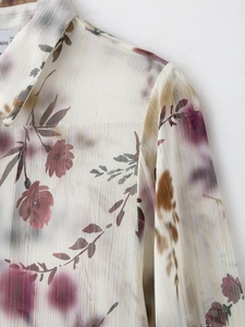 Dettaglio della camicetta in chiffon a fiori con strisce metalliche e motivi di foglie