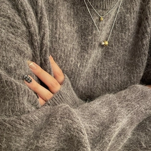 Close-up of dual silver and gold ball pendants layered on a 925 silver necklace