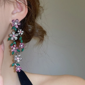 Close-up of vintage flower tassel earrings with pink zircons and green leaf gems