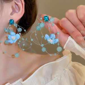 Detail of long blue floral tassel earrings featuring fabric petals and acrylic beads