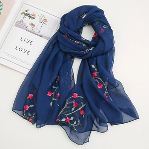 Detail of dark blue chiffon scarf with exquisite red flower embroidery and green leaves