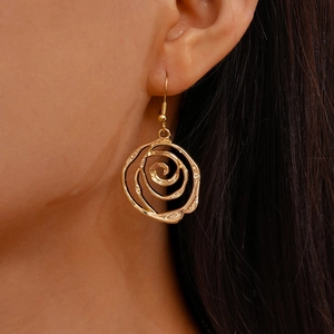 Detailed close-up of hollow spiral rose earrings in polished gold finish on a model