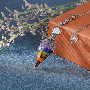 Chakra resin pendulum with colorful crystals and silver chain on a gift box