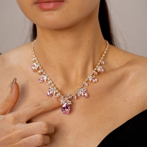 Détail du collier doré orné de zircons roses en forme de poire et de pierres marquise
