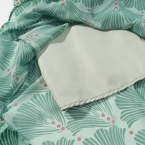 Detailed macro shot of the green chiffon floral dress hem showing fine stitching and inner lining