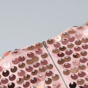Détail du tissu en maille à paillettes roses et fermeture éclair en métal argenté sur la robe