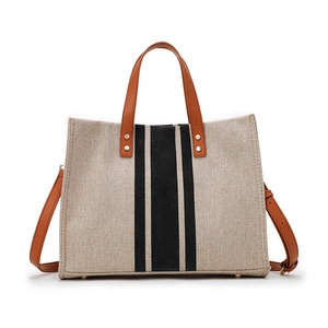 Elegant striped canvas tote bag with brown leather handles and adjustable shoulder strap