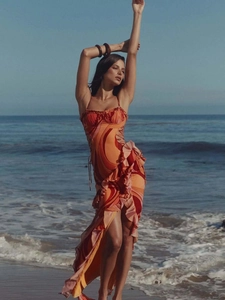 Detail of ruffled hem and high slit on vibrant orange abstract print summer sundress